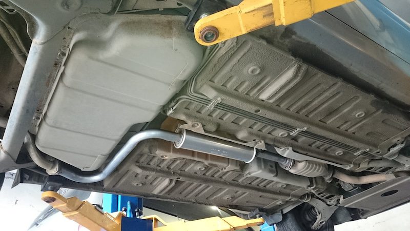 Резонатор выхлопной системы под днищем автомобиля на подъёмнике